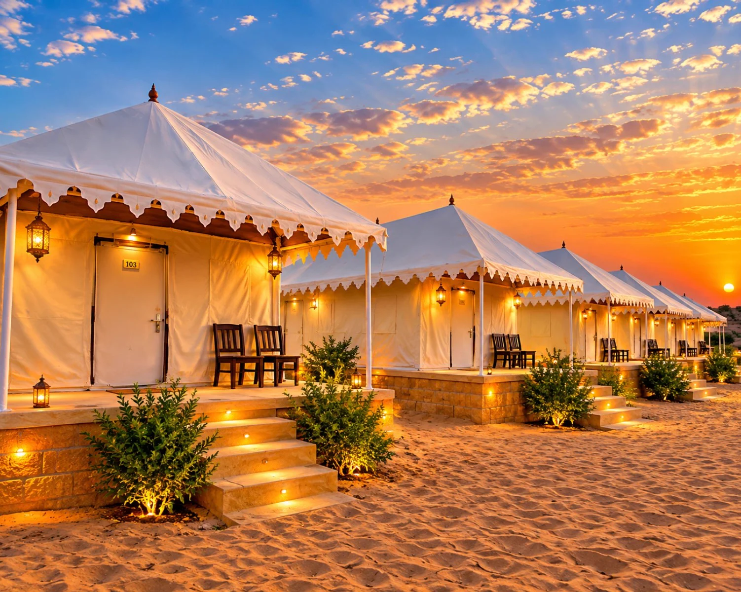 Row of luxury desert tents glowing with lanterns and warm lighting at dusk